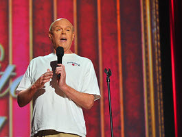a person in a white tee shirt speaking into a hand-held microphone